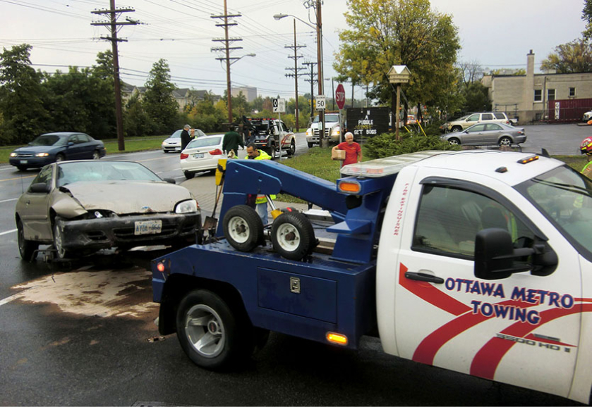 Ottawa Metro Towing truck responding to a car accident scene with damaged vehicle