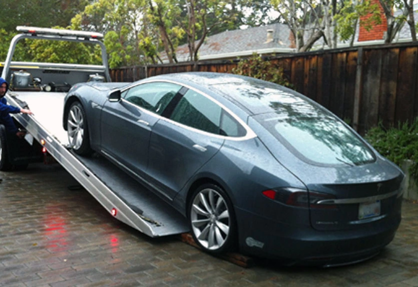 Tesla Model S being carefully loaded onto a flatbed tow truck using specialized equipment